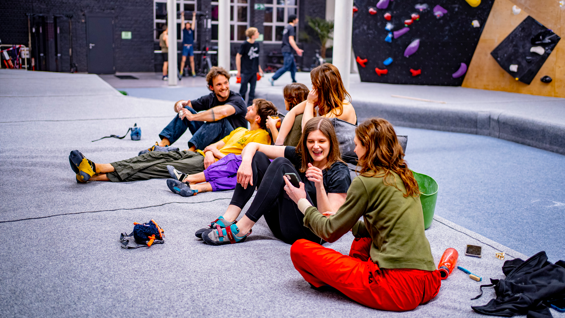 Walden Gent cursussen groepen Initiatielessen klimtechniek: Groep blije klimmers rust uit en socialiseert op de valmatten na een sessie of initiatieles in Walden Gent.