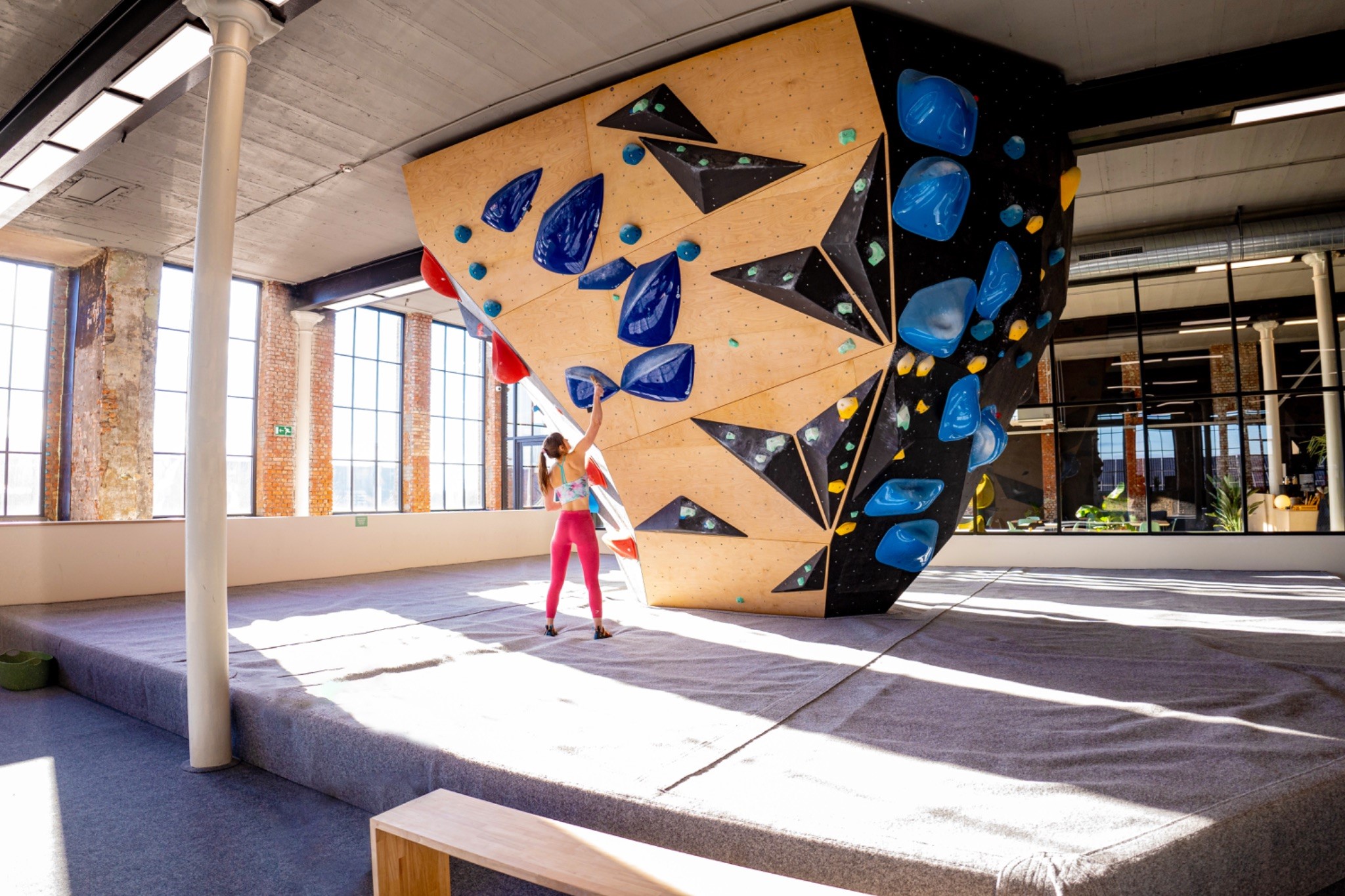 Walden, the largest bouldering hall in Ghent Belgium: Woman climbs on a modern, bright climbing wall in the spacious indoor bouldering hall in Ghent.